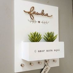 there is a white sign with succulents on it and a name tag attached to the wall