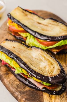 there is a sandwich with lettuce, tomato and cheese in it on the cutting board