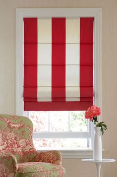 a red and white striped roman blind in a living room with a floral patterned chair