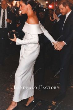 a woman in a white dress is shaking hands with a man wearing a suit and tie