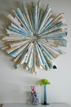 a clock made out of newspapers on the wall next to a vase with scissors in it