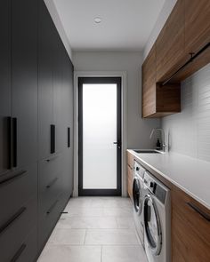 a washer and dryer in a room with wooden cabinets on either side of the door