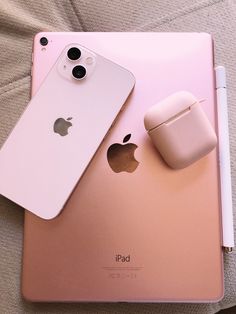 an apple phone and headphones are sitting on top of the back cover of a pink ipad