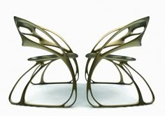 two metal sculptures sitting next to each other on a white surface and one is shaped like a butterfly