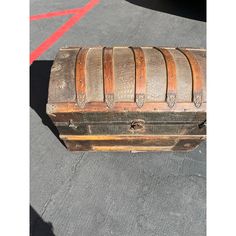 an old wooden trunk sitting on the ground next to a red line and white stripe