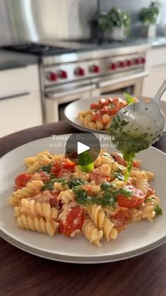 a white plate topped with pasta covered in sauce and vegetables next to a stove top oven