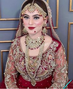 a woman wearing a red and gold bridal outfit