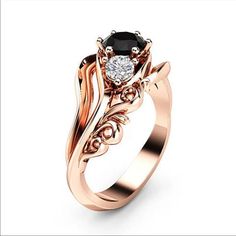 a rose gold engagement ring with an oval black diamond in the center and leaves on each side