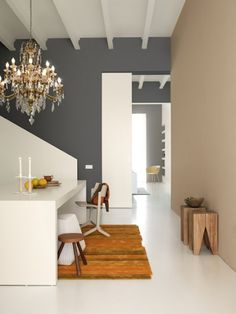 a white room with a chandelier hanging from the ceiling and chairs on the floor