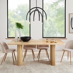 a dining room table with chairs and a vase on it in front of a large window