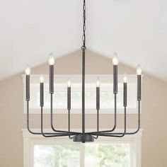 a chandelier hanging from the ceiling in a dining room with white walls and windows