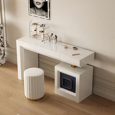 a white table with a mirror, stool and pictures on the wall in front of it