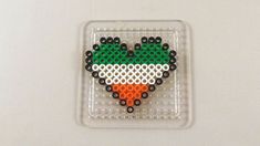 a piece of art made out of legos on a white surface with black and green beads