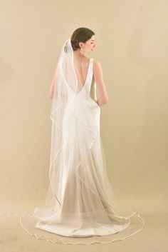 a woman in a white wedding dress with a veil on her head is looking back