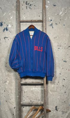 Extremely rare 1980s Buffalo Bills Cliff Engle jacket by Pro Elite. Officially licensed NFL product . Pin stripe , fully lined knit sweater jacket. Made in USA. Perfect size , fits like large. Like new , never worn condition . Brand: Cliff Engle by Pro Elite Size: tagged Medium , fits Large  Bust : 22  inches Sleeve: 21 inches Length: 27 inches Retro Crew Neck Outerwear With Ribbed Cuffs, Retro Oversized Crew Neck Outerwear, 90s Crew Neck Outerwear For Fall, 90s Style Outerwear With Crew Neck For Fall, Fitted Vintage Outerwear With Crew Neck, Fitted Vintage Long Sleeve Sweatshirt, Vintage Long Sleeve Track Jacket For Winter, Fitted Long Sleeve Vintage Sweatshirt, Vintage Fitted Crew Neck Outerwear