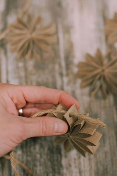 a person holding something in their hand on top of a wooden table with twine