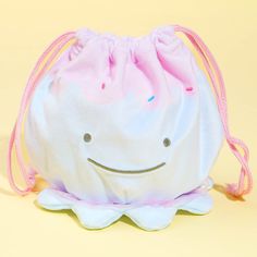 a white bag with a smiling face on the front and pink drawstring around it