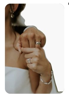 a woman in a white dress holding the hand of a man wearing a wedding ring