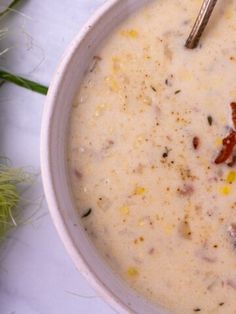 a white bowl filled with soup sitting on top of a table next to some flowers