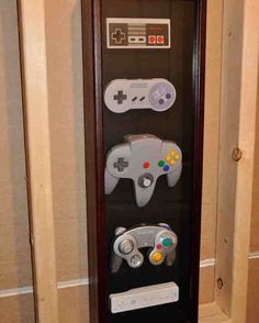 a display case with two video game controllers in front of it on the wall next to a toilet