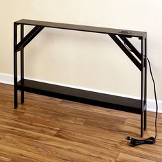 a black table sitting on top of a hard wood floor next to a white wall