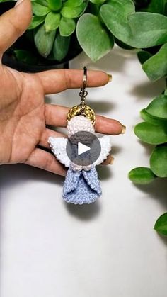 a hand holding a small keychain with an angel on it's side