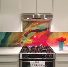 a stove top oven sitting inside of a kitchen next to a vase filled with flowers