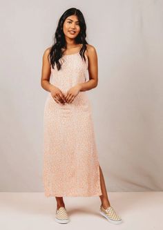 a woman standing in front of a white background wearing an orange and pink floral print dress