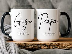 two coffee mugs with the names gigi and papa printed on them sitting on a wooden table