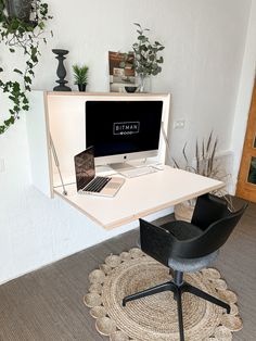 a desk with a laptop on it and a chair next to it in front of a plant