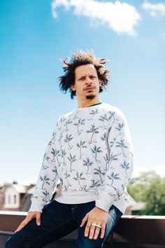 a man sitting on top of a roof with his hair in the air and looking off into the distance