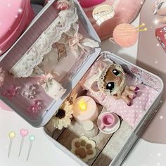 a small doll in a pink suitcase on a table with other dolls and decorations around it