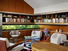 a living room filled with furniture and bookshelves next to a window covered in lots of books