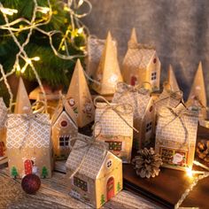 small christmas houses are sitting on a table next to a christmas tree and pine cones