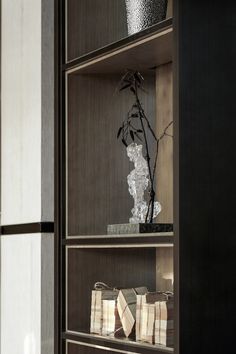 a book shelf with two vases on top of it and bags in front of it