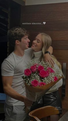 a man holding a bouquet of pink roses next to a woman in white shirt and black leather pants