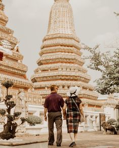 a man and woman walking in front of a tall building with intricately decorated spires