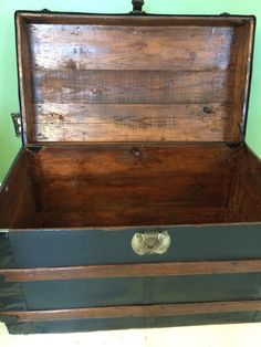 an old wooden trunk is sitting on the floor in front of a green painted wall