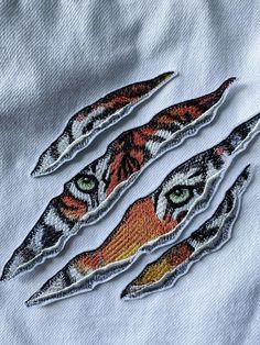 three pieces of embroidered fabric with an image of a cat's face