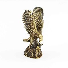 an eagle figurine sitting on top of a wooden stump with its wings spread