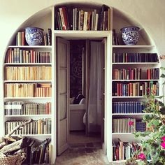 an arched doorway leads to a well - lit room with bookshelves full of books