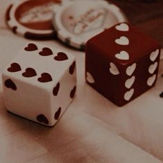 two dices sitting on top of a table next to each other with hearts painted on them