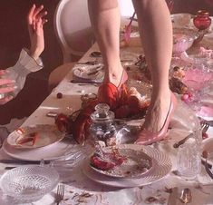 two people standing over a table with plates and silverware