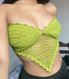 a woman wearing a green crochet top and black pants