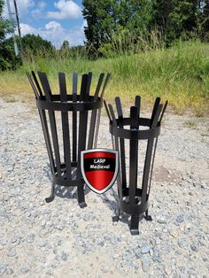 two metal trash cans sitting on top of a gravel field