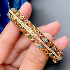 Enjoy timeless elegance with our Navaratna bangle featuring stunning gold plating and intricate jadau detailing in a vibrant array of colors. This exquisite piece will elevate any outfit and bring a touch of luxury to your jewelry collection. Navratna Bangles, Jadau Bangles, Jadau Jwellery, 22k Gold Jewelry Necklaces, 22k Gold Jewelry, Bangle Gold, Pearl Necklace Set, Gold Jewelry Necklace, Emerald Necklace