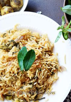 a white plate topped with rice and greens next to a bowl of potatoes on a table