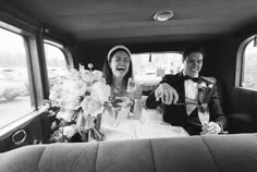 a bride and groom sitting in the back of a pick up truck with champagne flutes