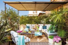 an outdoor living area with couches, tables and potted plants on the deck