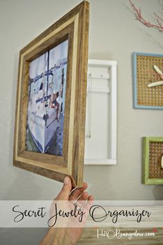 a person holding up a framed photo in front of a wall